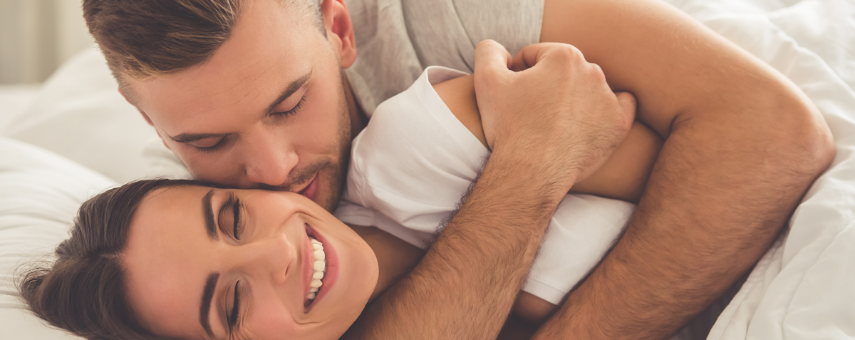 Ein Mann und eine Frau üben hormonfreie Verhütung, während sie sich im Bett umarmen.