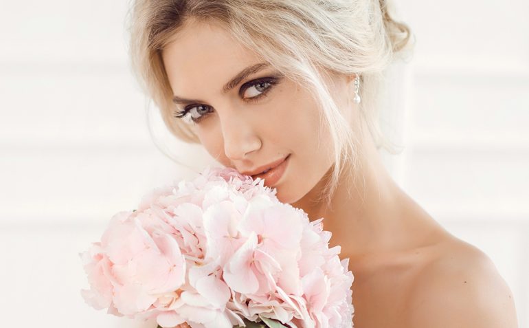Sanfte Eleganz: Eine Frau blickt nachdenklich, während sie zartrosa Blumen hält