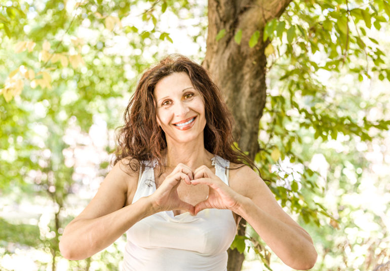 Eine Frau formt mit ihren Händen ein Herz und drückt damit Liebe und Zuneigung aus.