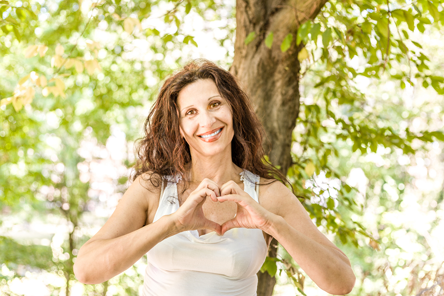 Eine Frau formt mit ihren Händen ein Herz und drückt damit Liebe und Zuneigung aus.