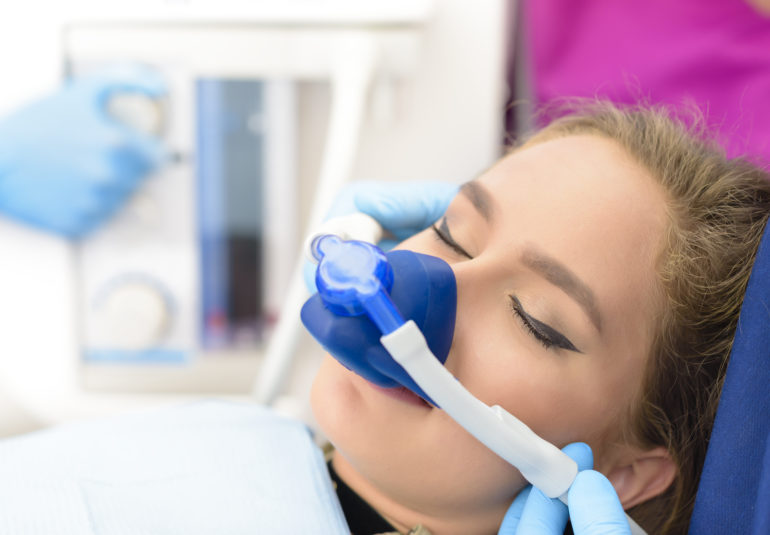 Eine Frau mit blauer Maske in einer Praxis erhält Narkose mit Lachgas.