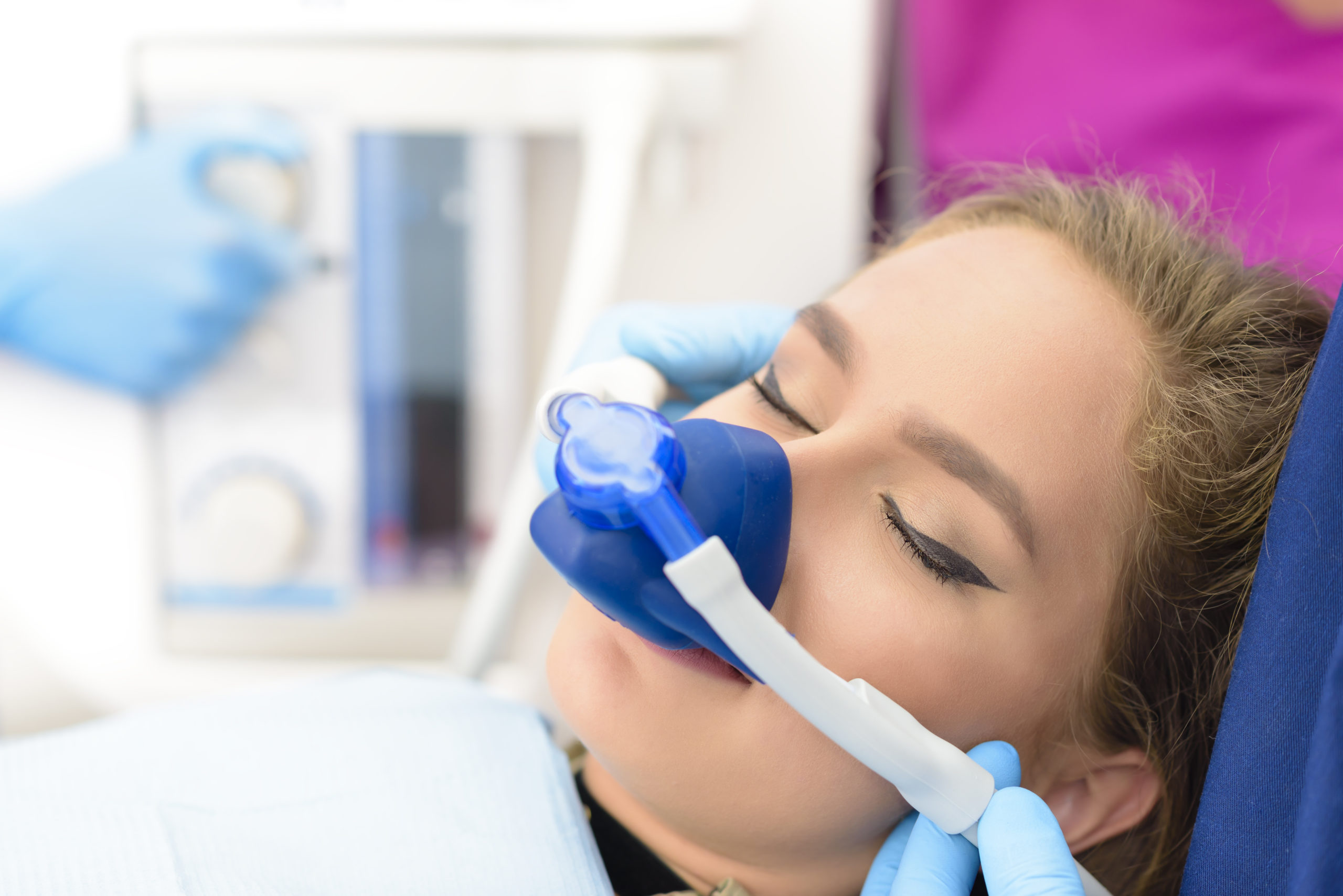 Eine Frau mit blauer Maske in einer Praxis erhält Narkose mit Lachgas.